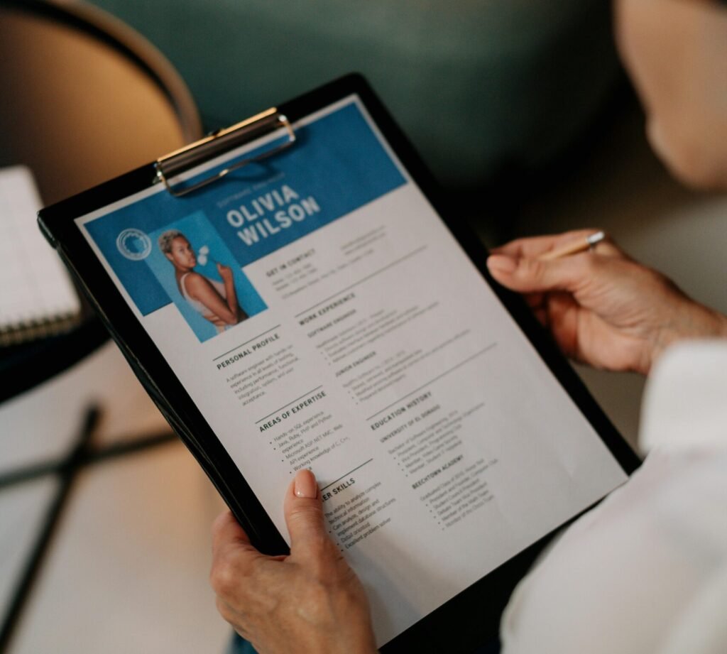 An HR professional reviews a resume on a clipboard during an office meeting.